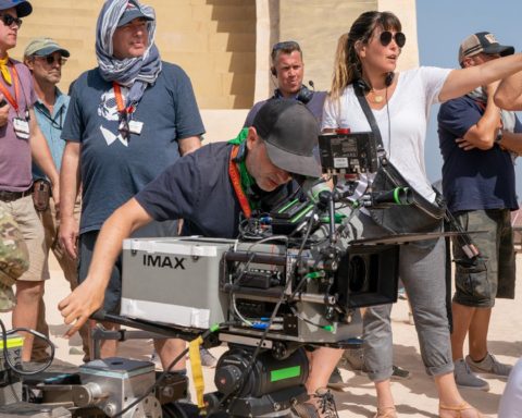 Cinematographer Matthew Jensen ASC at the IMAX film camera, with Patty director and crew, during production on Warner Bros.’ Wonder Woman 1984. Photo by Clay Enos. Copyright © 2018 Warner Bros. Entertainment Inc.